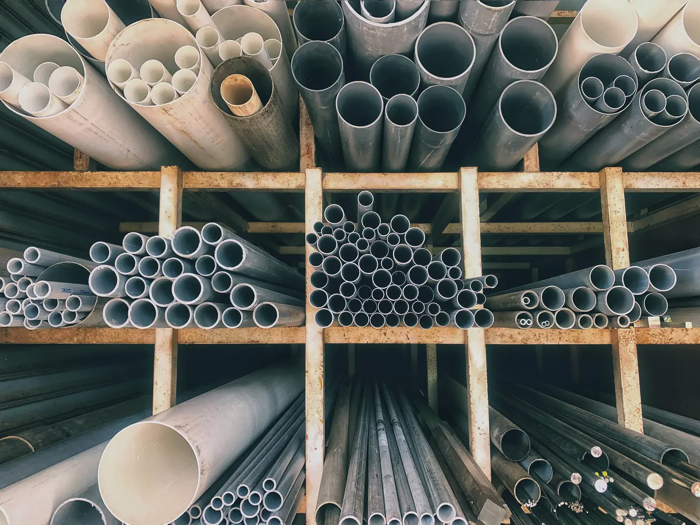 Assorted stainless steel pipes stacked in a warehouse, showcasing diverse sizes and high-quality materials