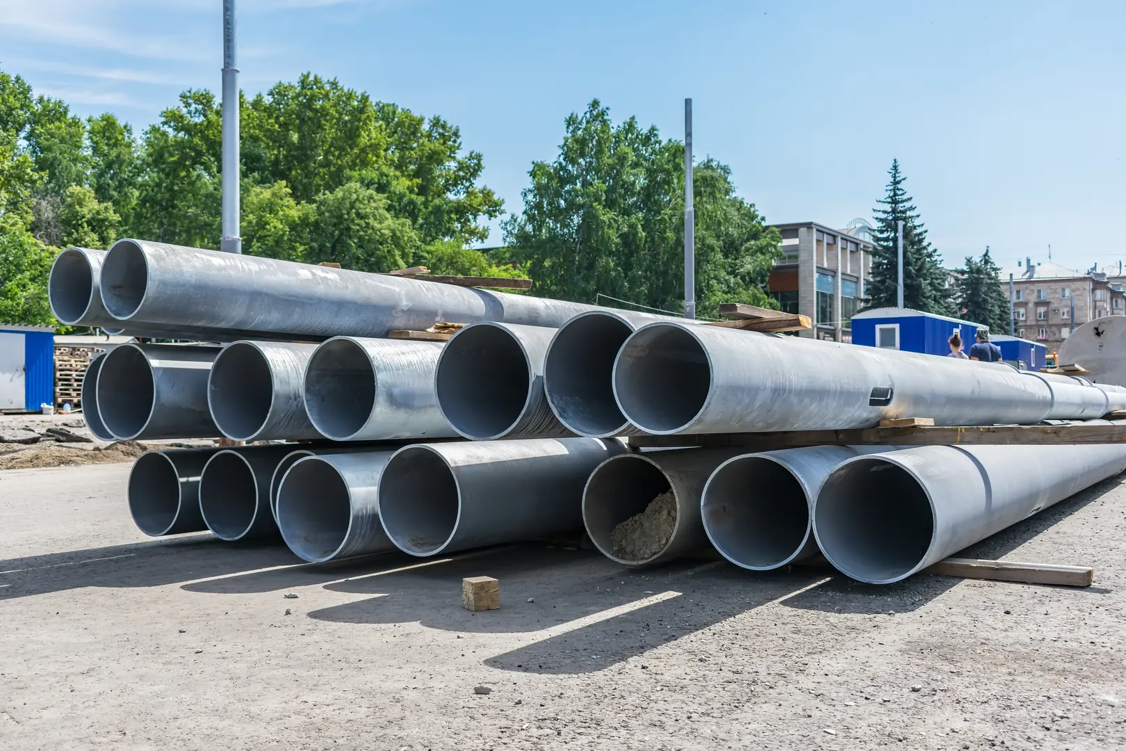Stack of large stainless steel pipes at an outdoor industrial site